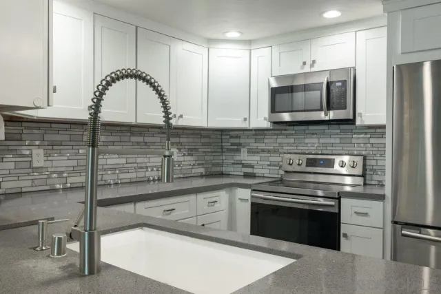 a kitchen with stainless steel appliances granite countertop a stove a sink and a microwave