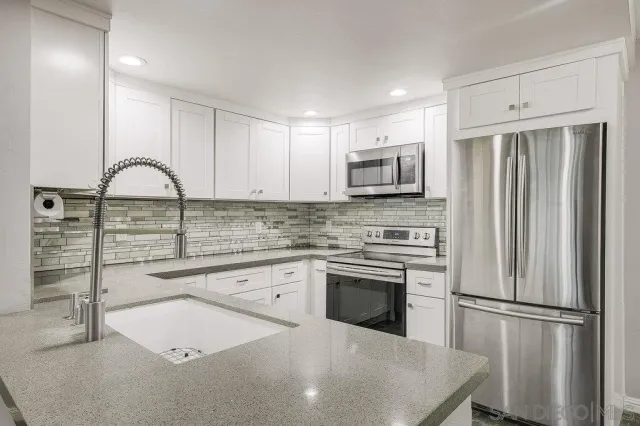 a kitchen with stainless steel appliances granite countertop a refrigerator sink and stove