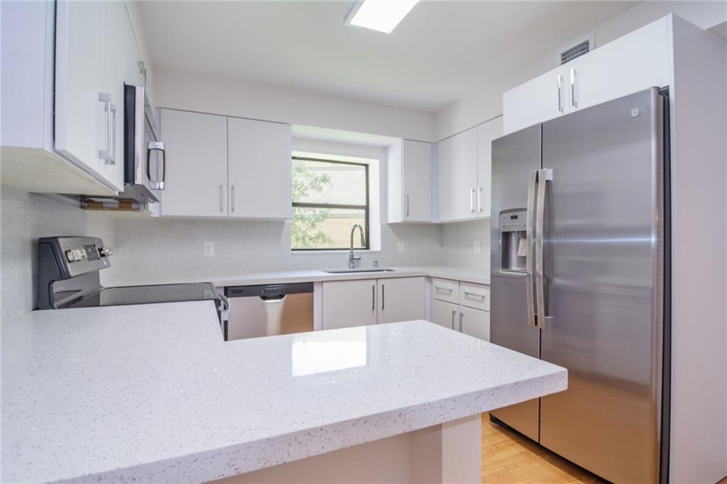 a kitchen with kitchen island a counter top space a sink and stainless steel appliances