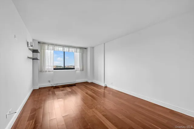 an empty room with wooden floor cabinet and windows