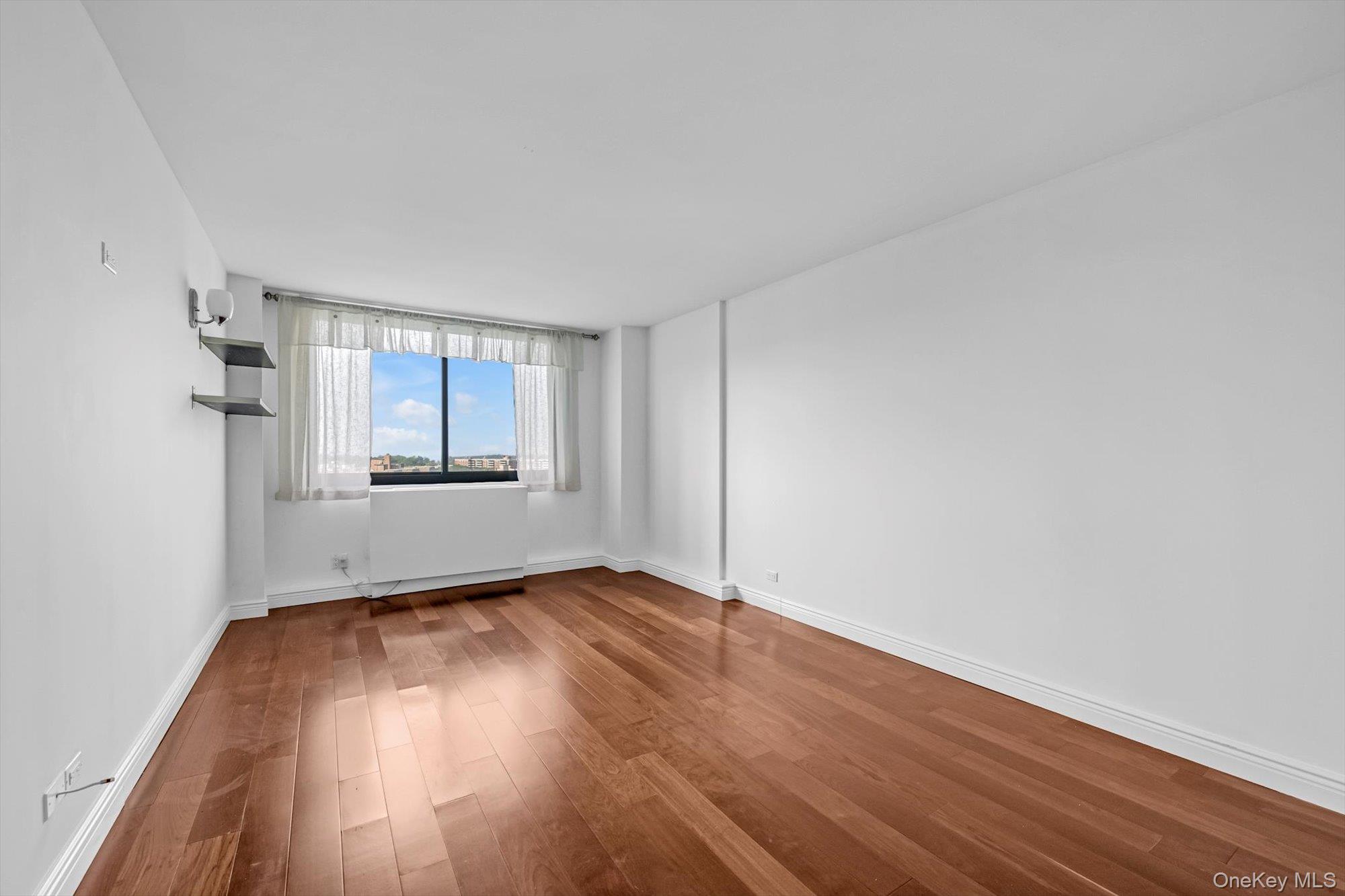1 Bay Club Drive, Unit 8J Queens, NY 11360 - Photo 7 of 17 an empty room with wooden floor cabinet and windows