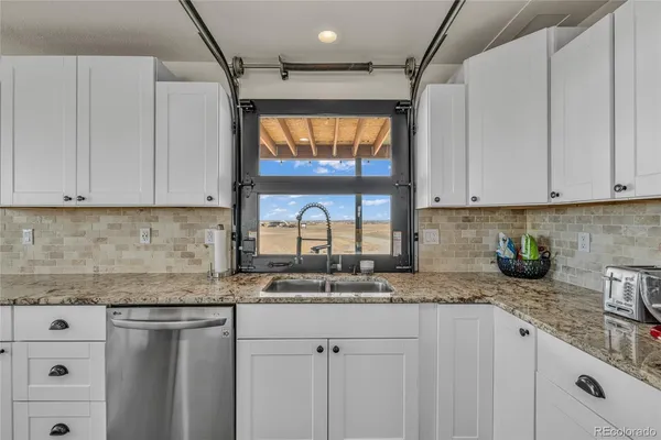 a kitchen with granite countertop white cabinets white appliances and a sink