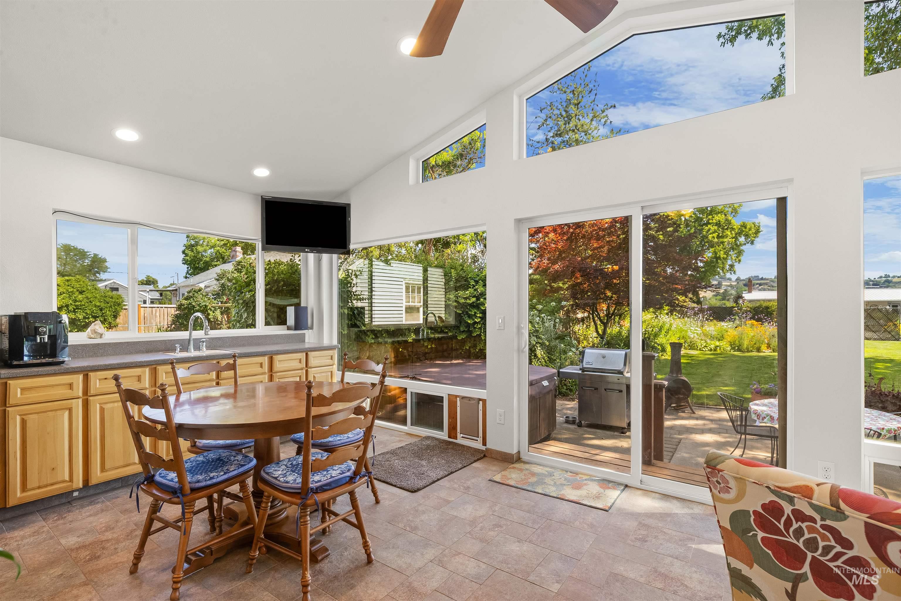 924 N Street Lewiston, ID 83501 - Photo 5 of 46 Bright sunroom featuring expansive windows, vaulted ceilings, sliding glass door access to the outdoor patio, a built-in countertop with wood-finish cabinetry, and recessed lighting