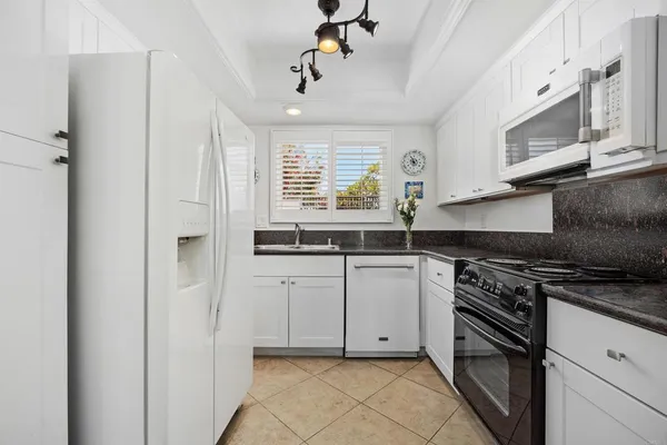 a kitchen with granite countertop white cabinets and white appliances