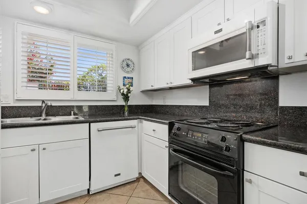 a kitchen with granite countertop white cabinets and a stove top oven