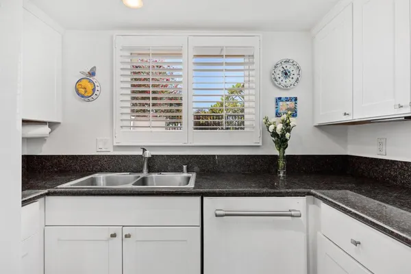a kitchen with granite countertop white cabinets white countertops and window