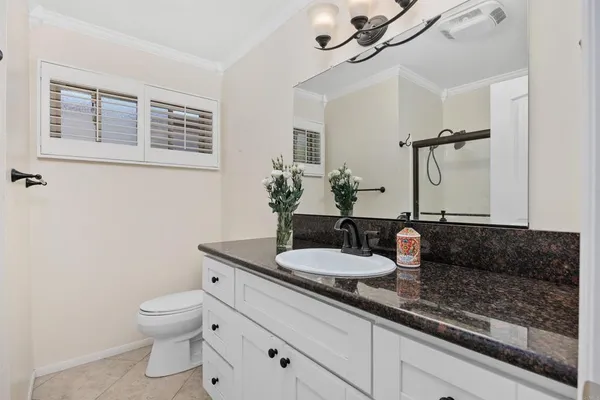 a bathroom with a granite countertop sink a toilet and mirror