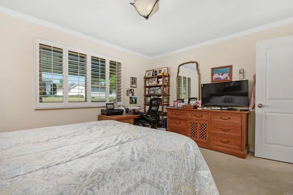 a bedroom with a large bed and a flat tv screen on dresser