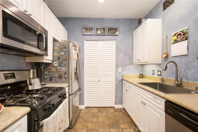 a kitchen with stainless steel appliances granite countertop a sink stove and refrigerator