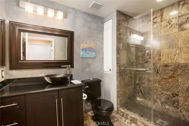 a bathroom with a granite countertop sink toilet and shower