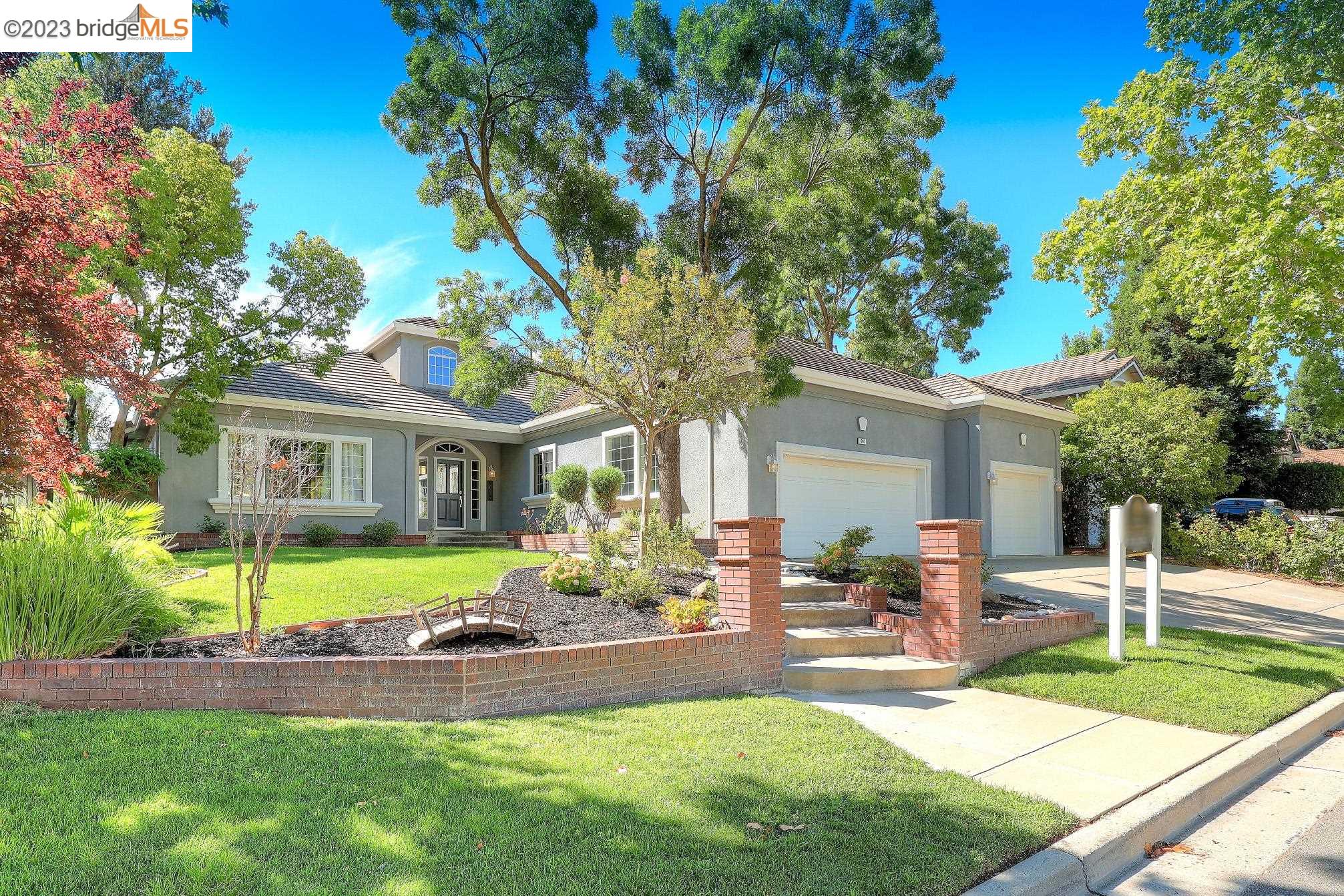 a front view of a house with garden and trees