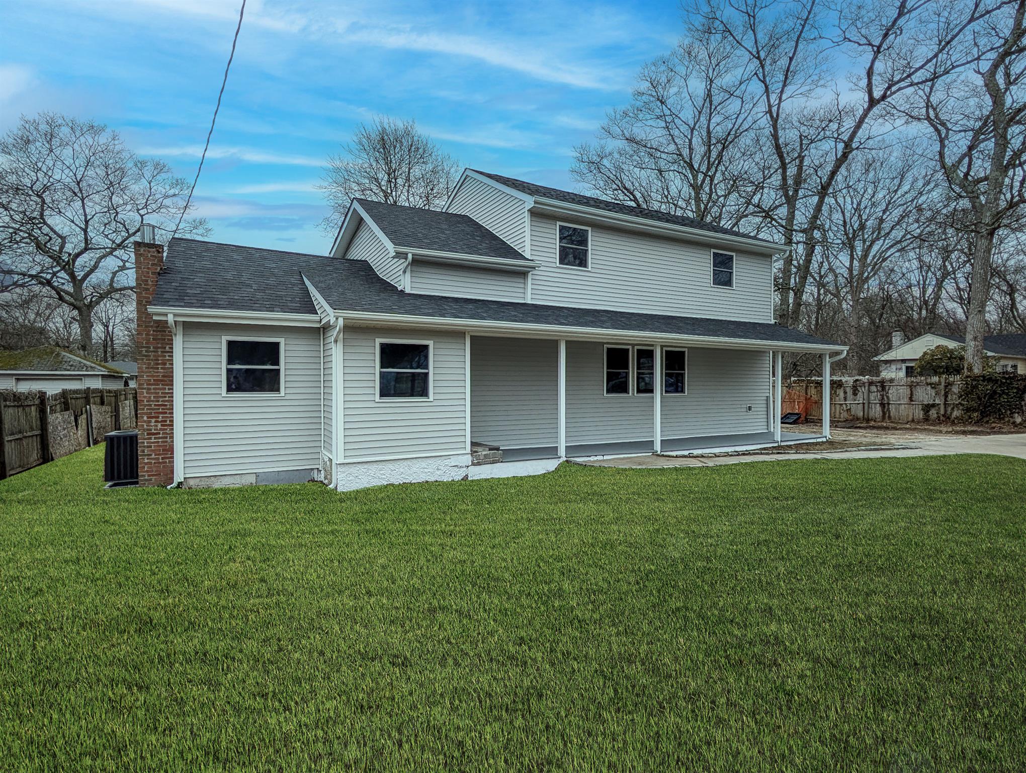 Rear view of house with a chimney, fence, a shingled roof, central AC unit, and a lawn