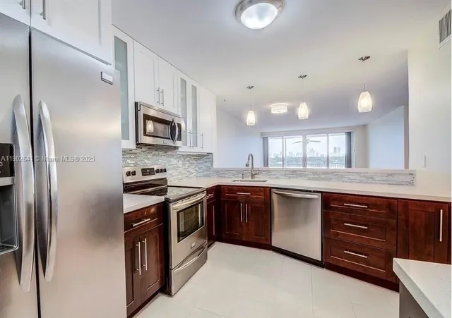 a large kitchen with stainless steel appliances granite countertop a stove a sink and a refrigerator