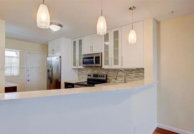 an empty room with kitchen view and a fireplace