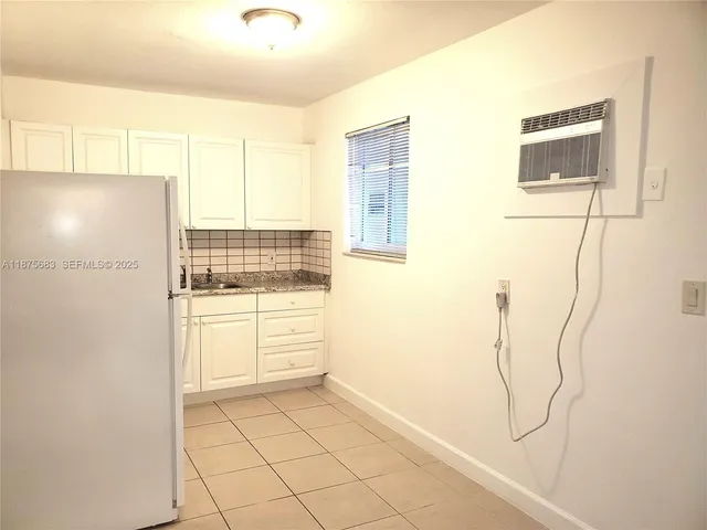 a kitchen with a refrigerator a stove top oven and cabinets