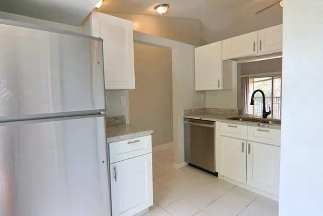 a kitchen with white cabinets and refrigerator