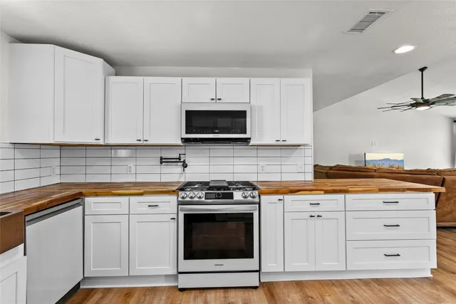 a kitchen with stainless steel appliances granite countertop a stove a sink and a microwave