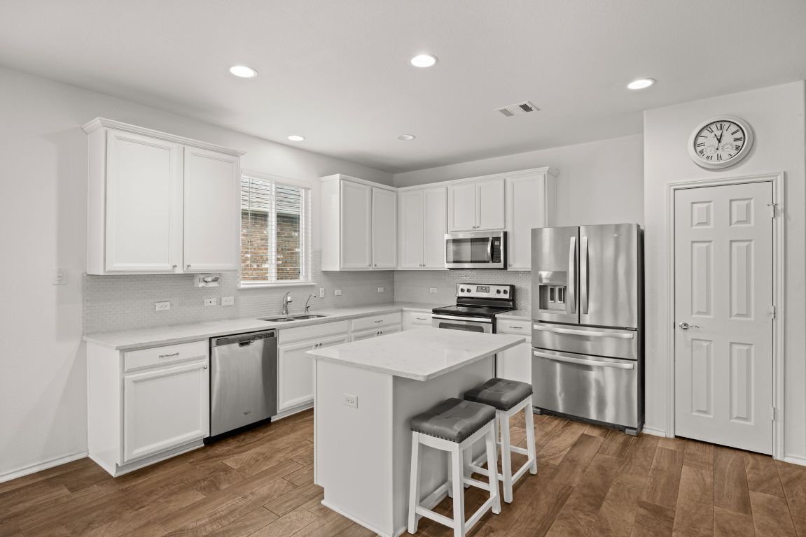 125 Hopen Cove Leander, TX 78641 - Photo 4 of 20 a kitchen with white cabinets and stainless steel appliances
