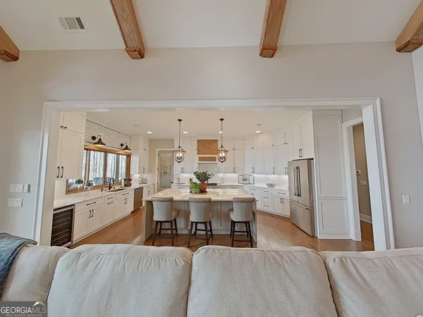 a living room with stainless steel appliances furniture and a kitchen view