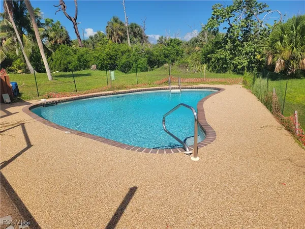 a view of a swimming pool with a yard and large trees