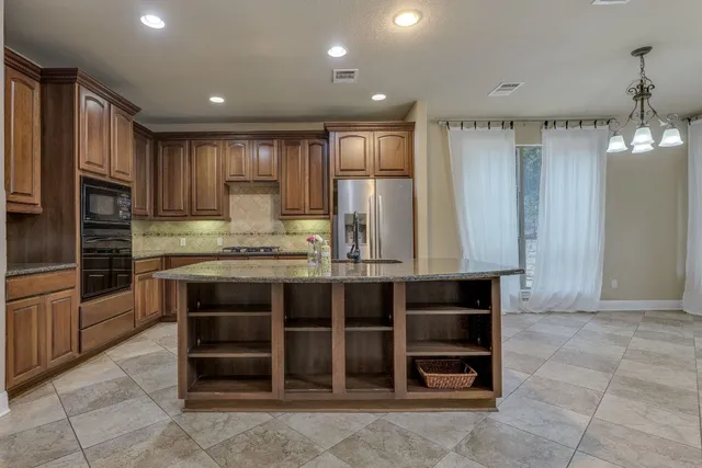 a kitchen with stainless steel appliances granite countertop a refrigerator and a stove top oven