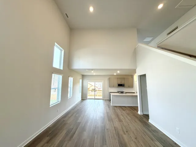 a view of empty room with wooden floor and kitchen view