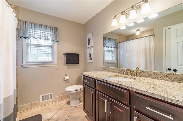 a spacious bathroom with a granite countertop sink a toilet and a large mirror