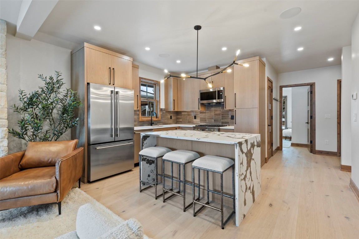 203 North Ridge Street, Unit B Breckenridge, CO 80424 - Photo 13 of 49 Kitchen with light brown cabinets, light stone countertops, a kitchen breakfast bar, stainless steel appliances, and a kitchen island