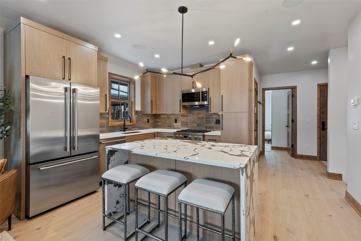 203 North Ridge Street, Unit B Breckenridge, CO 80424 - Photo 14 of 49 Kitchen with light brown cabinetry, stainless steel appliances, light stone countertops, a breakfast bar, and a kitchen island