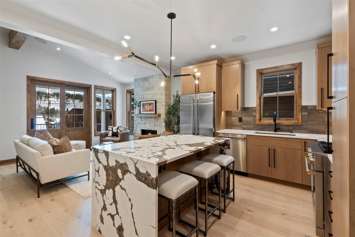 203 North Ridge Street, Unit B Breckenridge, CO 80424 - Photo 15 of 49 Kitchen with a kitchen bar, a kitchen island, high quality appliances, light stone countertops, and backsplash