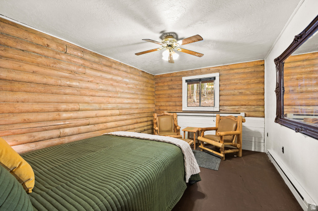 4725 Pine Ridge Road Evanston, UT 82930 - Photo 21 of 82 Room with natural wood log walls, a window overlooking trees, and a ceiling fan