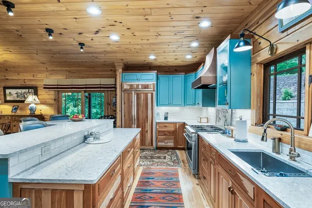 a very nice looking open kitchen with stainless steel appliances granite countertop a stove and a sink