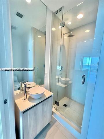 480 Northeast 31st Street, Unit 902 Miami, FL 33137 - Photo 17 of 33 a bathroom with a sink a toilet a mirror and shower