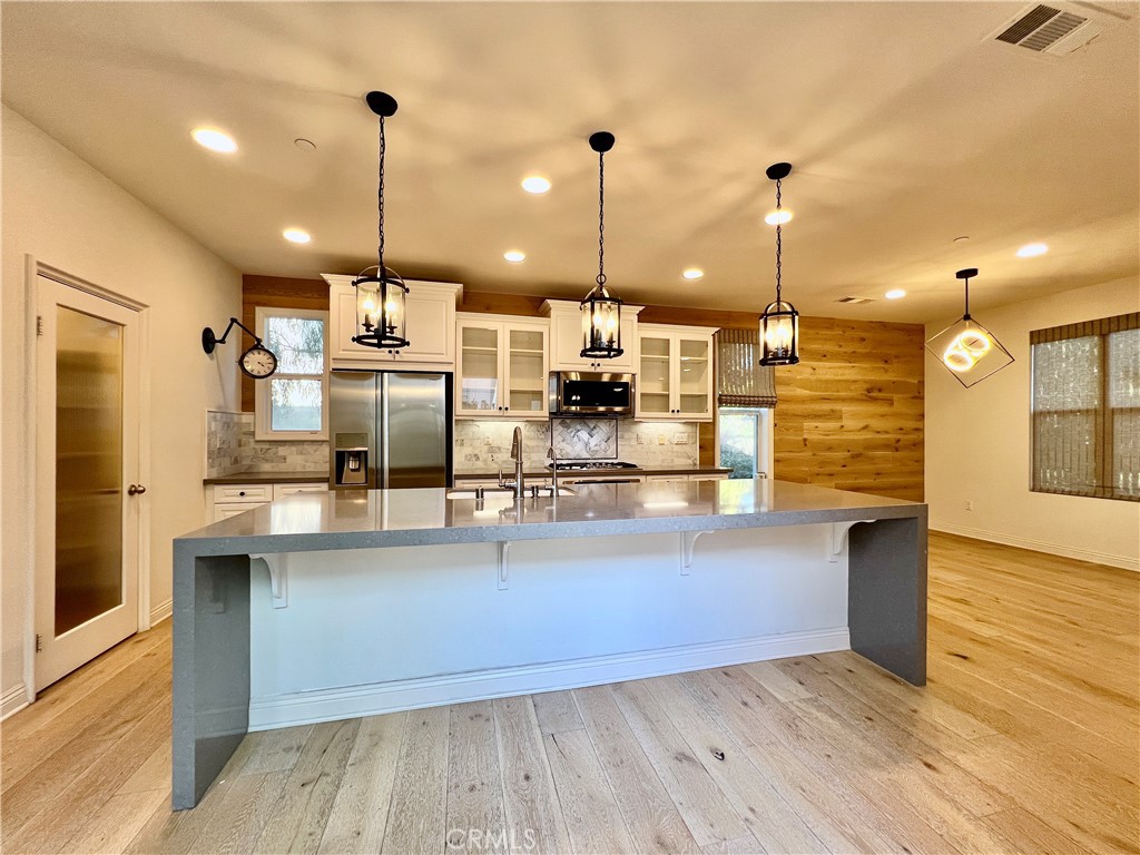 a view of a kitchen with kitchen island a counter space appliances and a ceiling fan