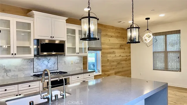 a kitchen with stainless steel appliances a stove a refrigerator a sink a dining table and chairs with wooden floor