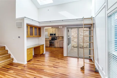 a living room with stainless steel appliances furniture wooden floor and a kitchen view