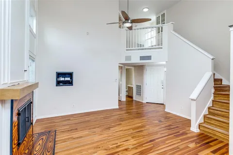 a view of an empty room with wooden floor and a fireplace
