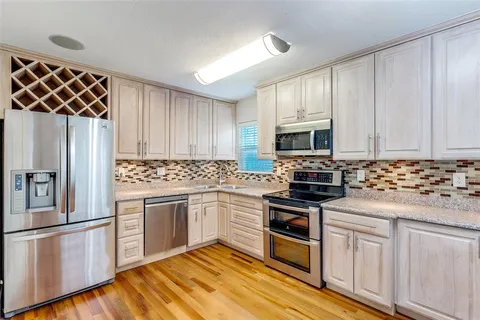 a kitchen with cabinets stainless steel appliances and wooden floor