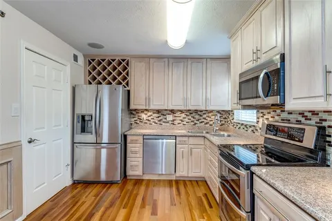 a kitchen with granite countertop a refrigerator stove and microwave