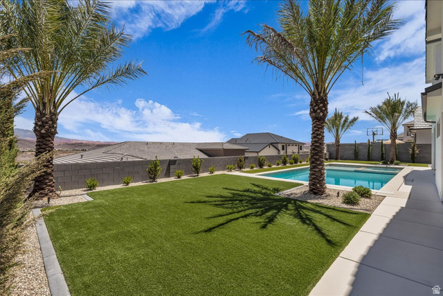 1620 Belayer Drive St. George, UT 84770 - Photo 44 of 51 Expansive backyard featuring a rectangular swimming pool, artificial turf, perimeter block wall, and mature palm trees