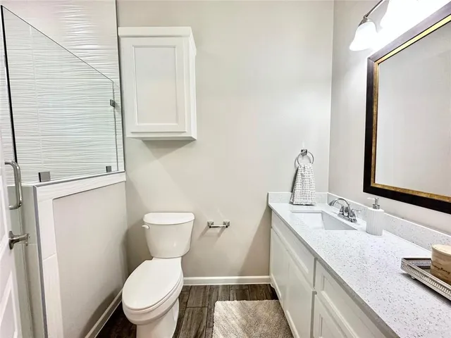 a bathroom with a granite countertop toilet sink and mirror