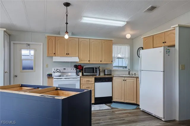 a kitchen with stainless steel appliances granite countertop a refrigerator a sink dishwasher a stove and white cabinets with wooden floor