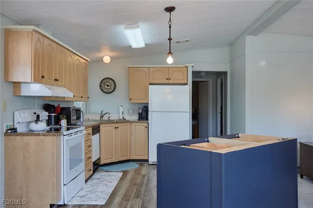 a kitchen with stainless steel appliances granite countertop a refrigerator a sink dishwasher a stove and white cabinets