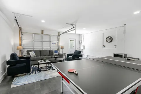 a living room with furniture pool table and wall paintings