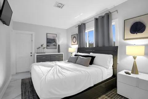 a bedroom with a bed a flat screen tv and dresser