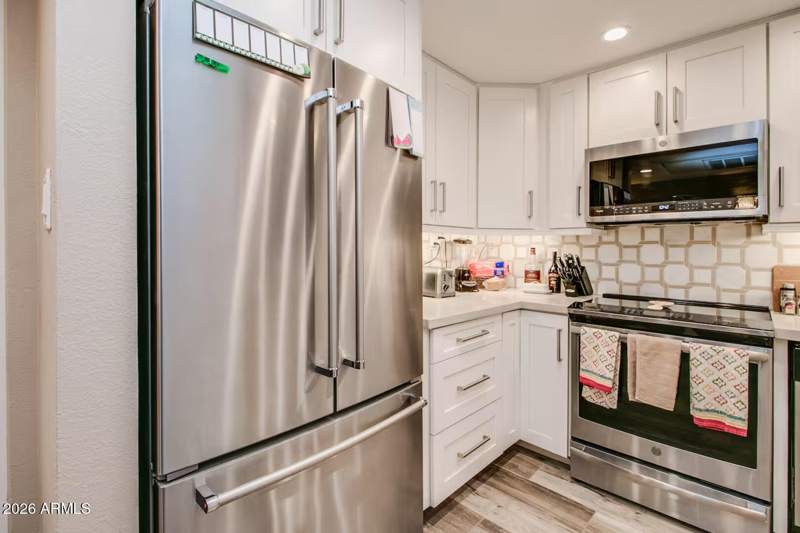 7625 East Camelback Road, Unit B133 Scottsdale, AZ 85251 - Photo 3 of 30 a kitchen with white cabinets and stainless steel appliances