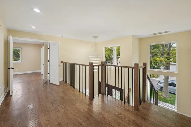 a view of a hallway with wooden floor and windows