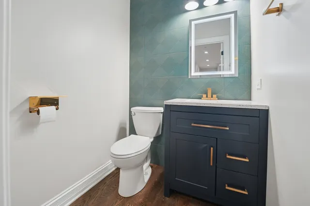 a bathroom with a toilet sink vanity and mirror