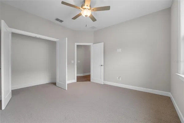 an empty room with a chandelier fan and a ceiling fan