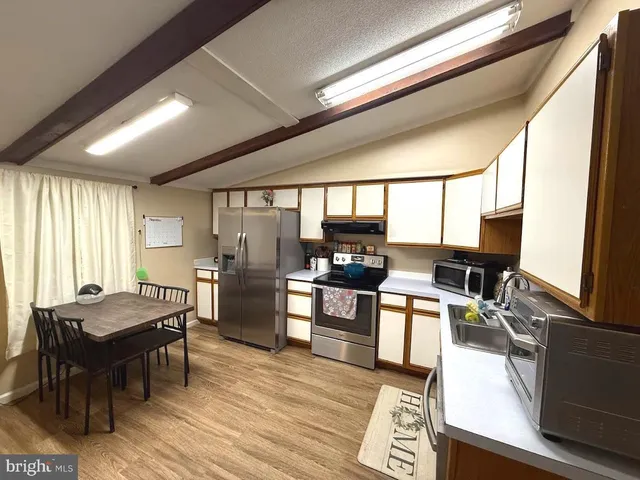 a kitchen with stainless steel appliances wooden floor dining table and chairs